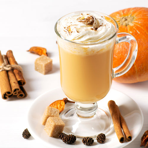 Pumpkin spice latte in a tall clear mug topped with whipped cream and a sprinkle of pumpkin pie spice.