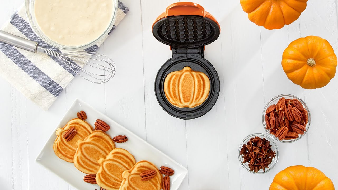Waffle batter is added to the maker and cooked to make pumpkin-shaped mini waffles.