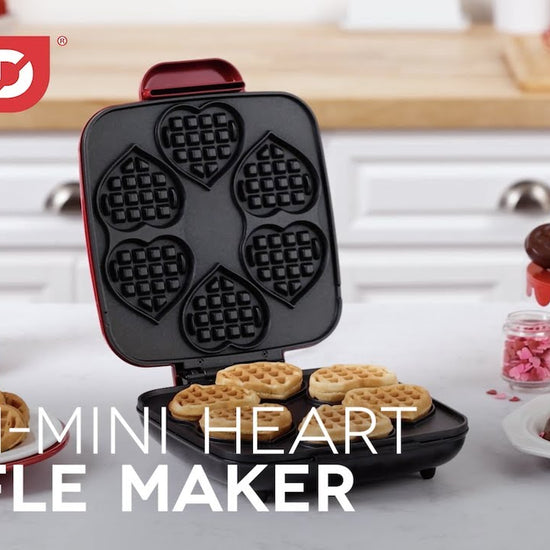 Waffle batter is added to the maker and cooked to make six mini heart-shaped waffles. The mini heart-shaped waffles are dipped in chocolate and decorated with sprinkles.