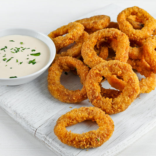 Crispy onion rings and a dipping sauce on a wooden plate.