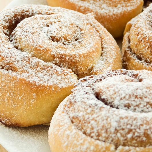 Cinnamon rolls on a plate topped with powdered sugar.