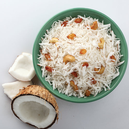A bowl of coconut thai rice with a coconut next to it.