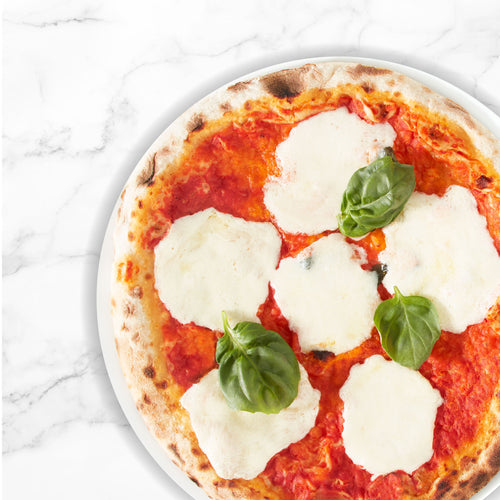 Top down view of a margherita pizze on a marble countertop.