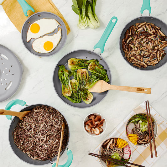 An overhead view of various pots and pans on a white marble countertop.