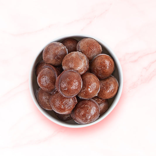 A stack of chocolate Donut Bites in a white bowl on a marble countertop.