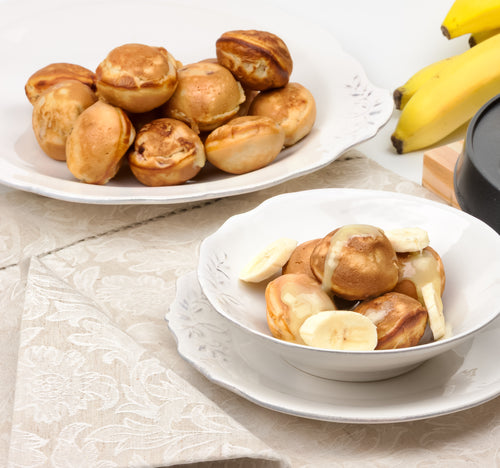 Two white bowls full of Banana Bread Donut Bites on a beige table cloth.