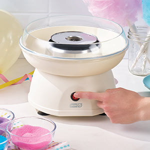Cotton candy machine on a table with colorful cotton candy and ingredients.