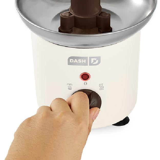 Hand adjusting a control on a Chocolate Fountain with 'DASH' branding.