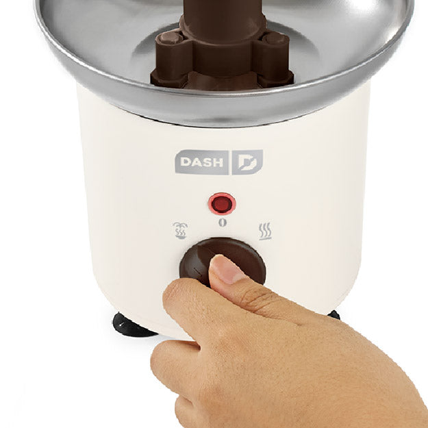 Hand pressing a button on a Chocolate Fountain Specialty Dash appliance