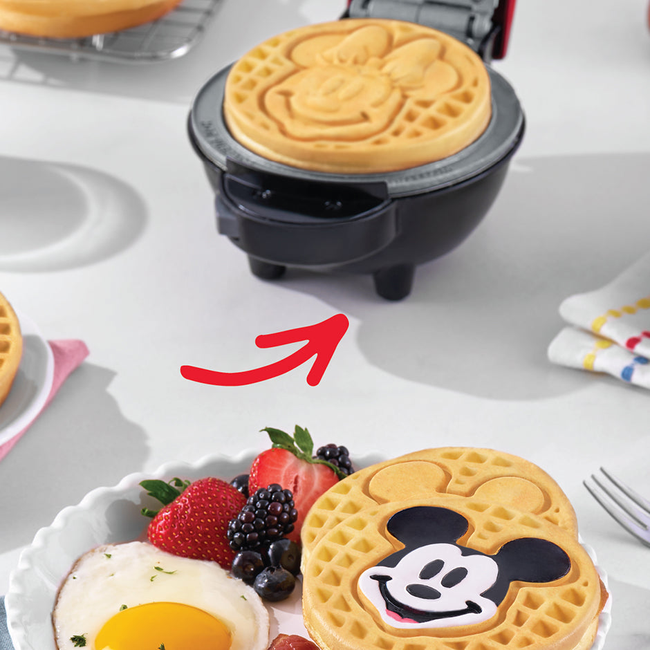 Disney Minnie Mouse waffle made with Dash | Disney MultiMaker™ Mini System, served alongside eggs, fruit, and a Mickey waffle.