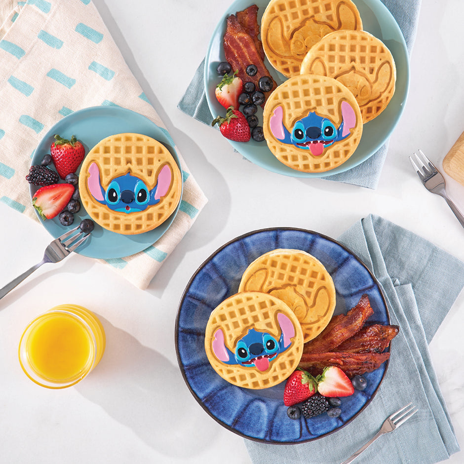 Plates with Stitch-shaped waffles served with bacon, berries, and orange juice, making breakfast fun and delicious for the whole family.