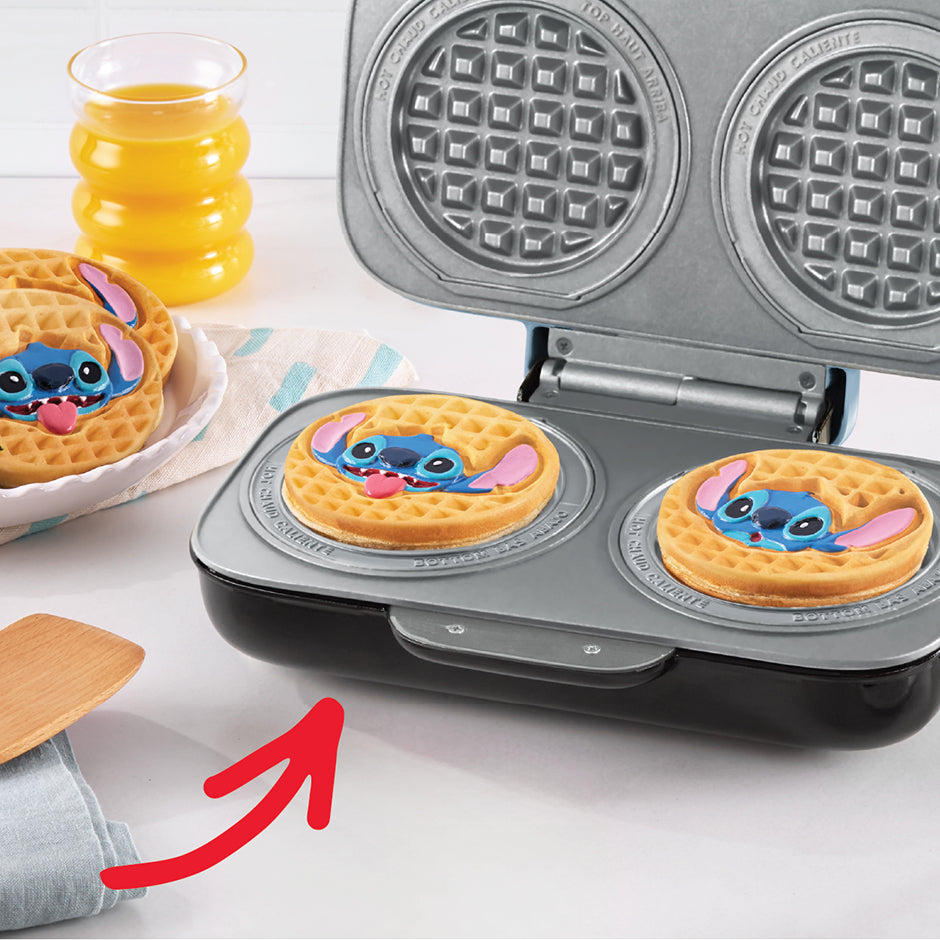 Disney | Dash Stitch MultiMaker™ Double Mini Maker System baking two golden Stitch waffles, served with juice for a fun family breakfast.