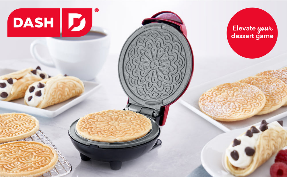 Dash Mini Pizzelle Maker baking fresh pizzelles beside coffee and cream-filled cannoli-style cookies.