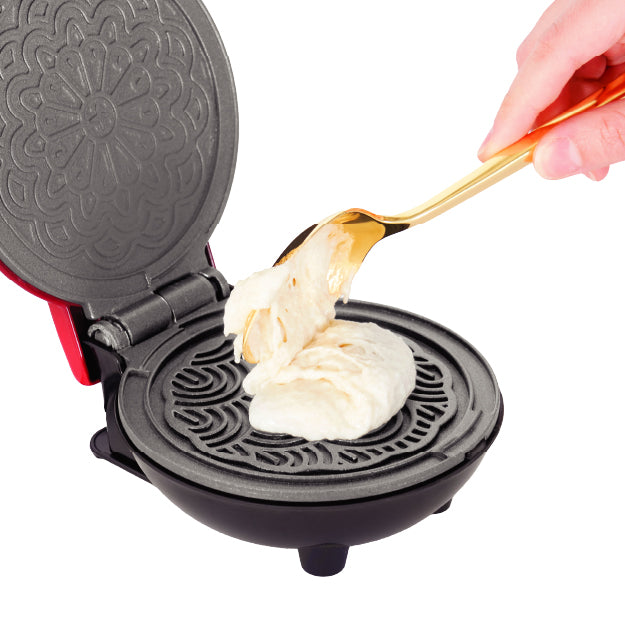 Hand spooning batter onto patterned nonstick plates of the Dash Mini Pizzelle Maker.