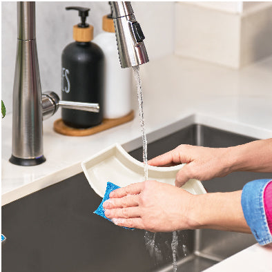 Person washing S’Mores Maker Specialty Dash under a running faucet in a kitchen sink.