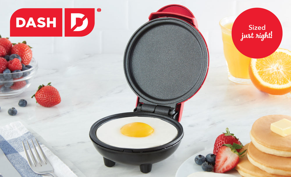 An red colored mini griddle maker sits open on a white counter.