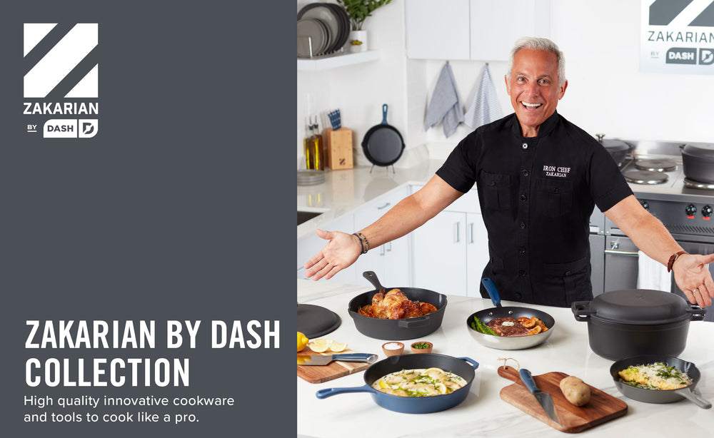 Geoffrey Zakarian in a kitchen wearing a black shirt gestures to the Zakarian by Dash collection on a white countertop.  