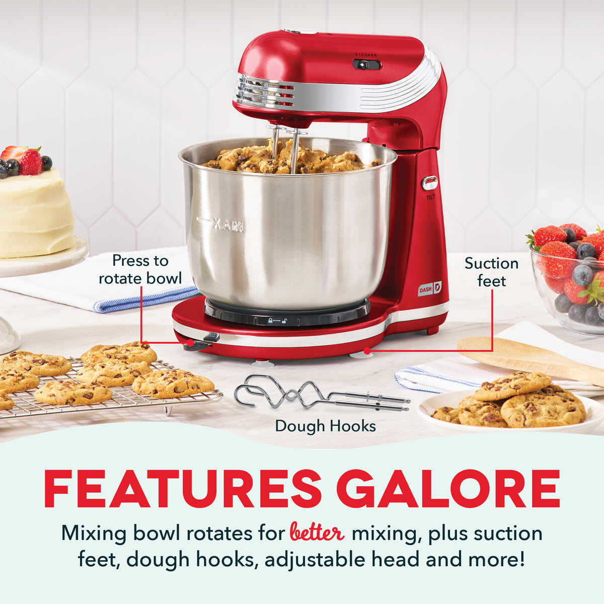 Red stand mixer with stainless steel bowl, dough hooks, and rotating base on kitchen counter with cookies and cakes nearby.