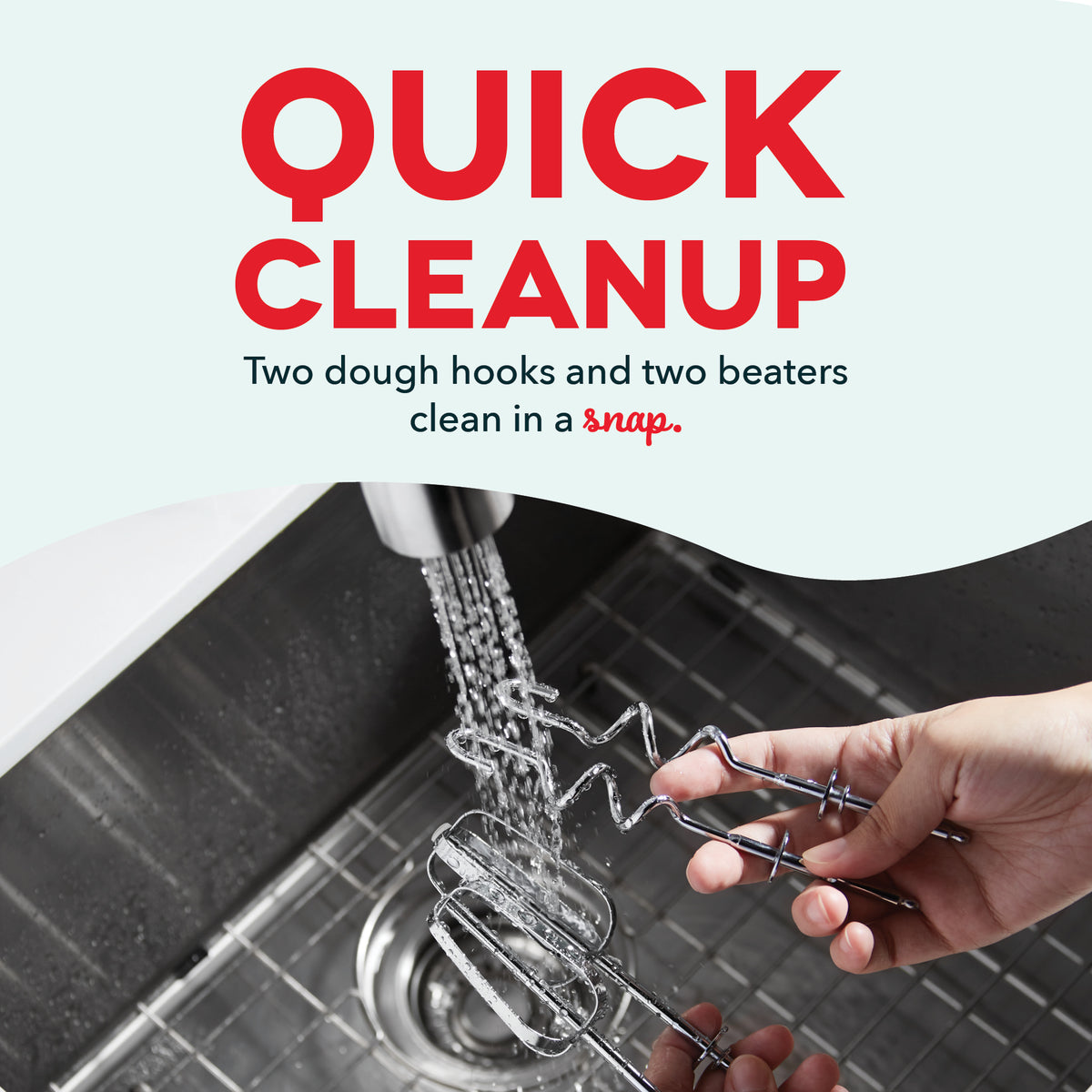 Hand rinsing two metal dough hooks and two wire beaters under running water in a sink.