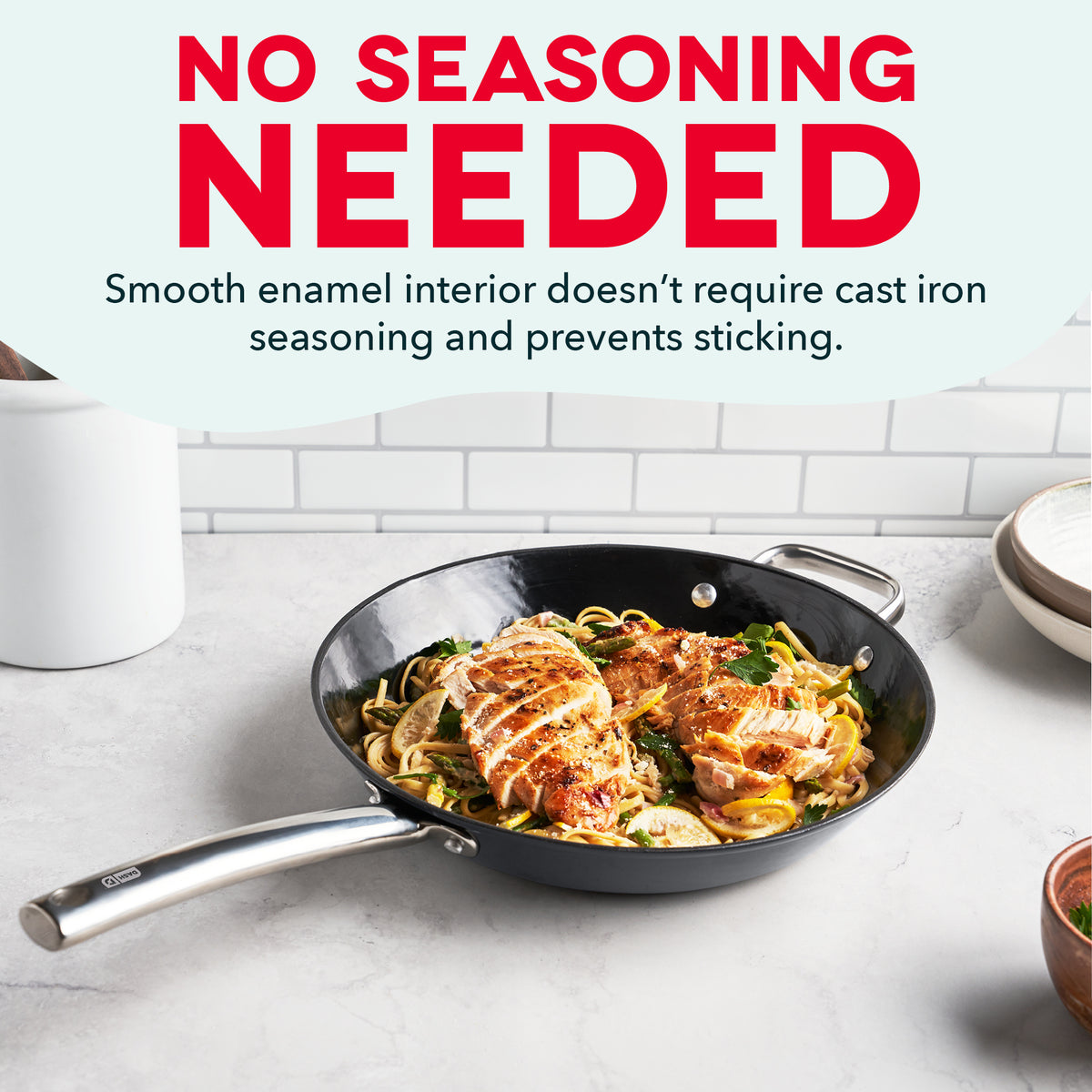 Black cast iron skillet with sliced chicken and noodles on white marble countertop.