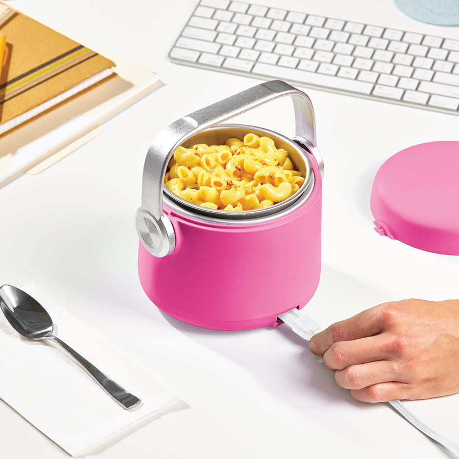 Hand plugging in the pink Dash Hot2Go™ Electric Lunchbox filled with mac and cheese—perfect for enjoying hot meals at your desk.