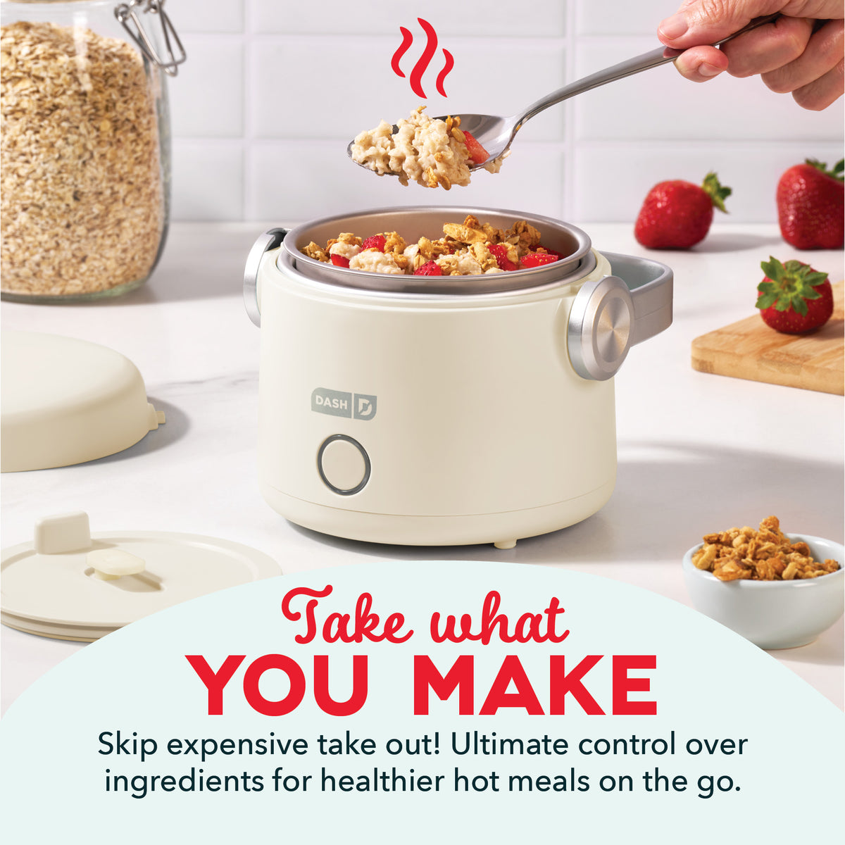 Cream-colored electric lunchbox with handles containing hot cereal and berries, spoon lifting food above, surrounded by ingre