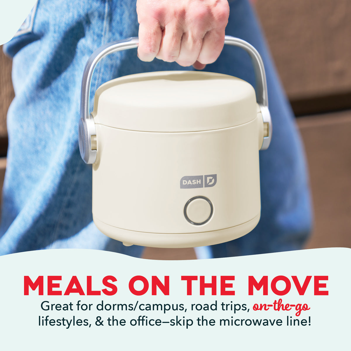Cream-colored electric lunchbox with carrying handle and power button, held by person in blue shirt.