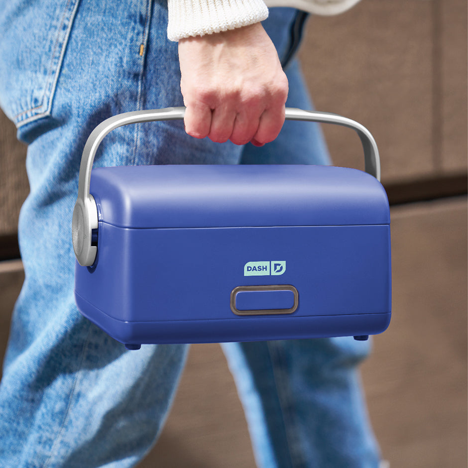 Person holding a blue electric lunch box with 'Dash' branding.