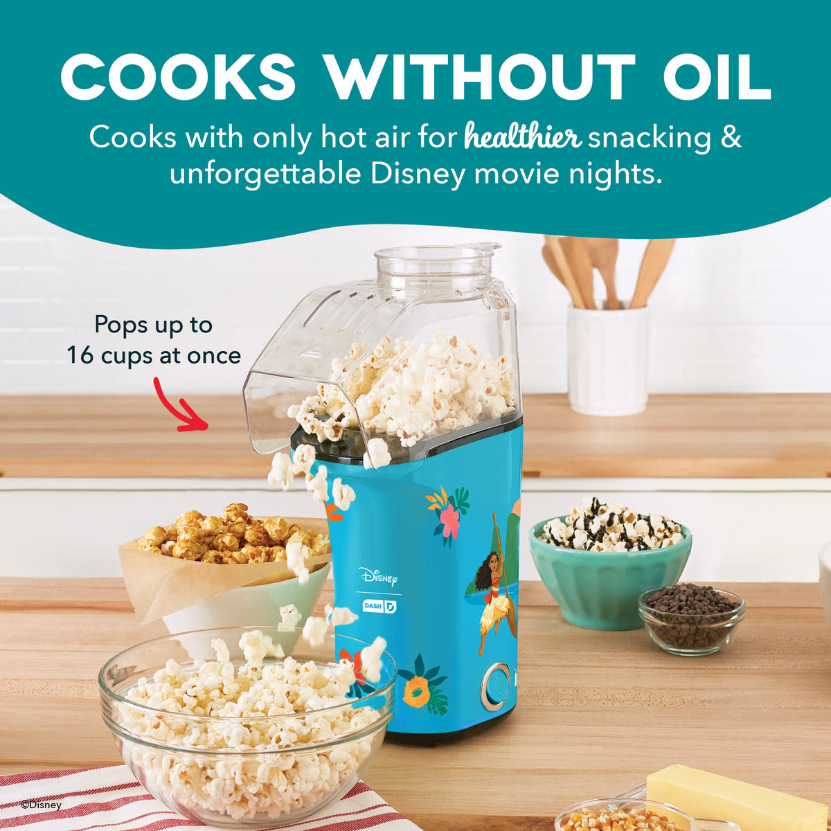 Teal Disney popcorn maker with clear top container filled with popcorn, surrounded by bowls of popcorn and kernels on wooden 