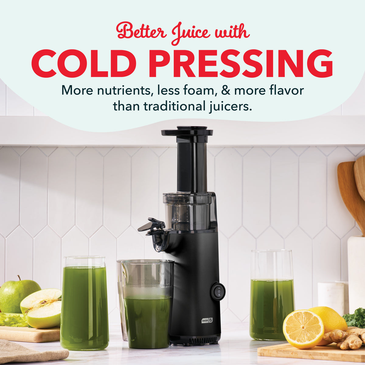 Black cold press juicer with collection pitcher, surrounded by fresh produce and glasses of green juice.