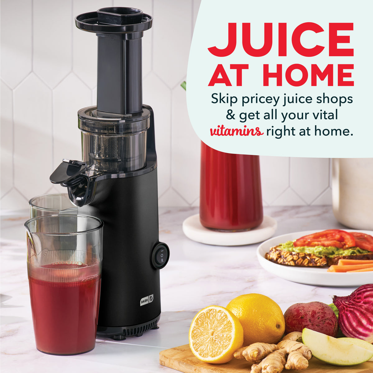 Black cold press juicer with collection glass dispensing red juice, surrounded by fresh fruits and vegetables.
