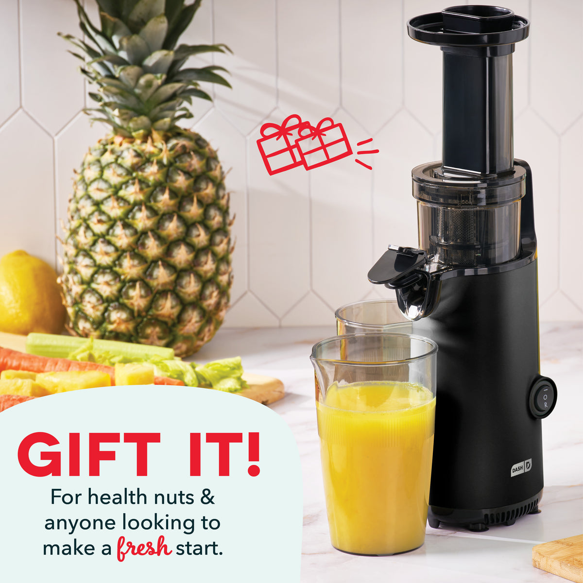 Black vertical cold press juicer with collection cup containing yellow juice, surrounded by pineapple, lemon, and vegetables.