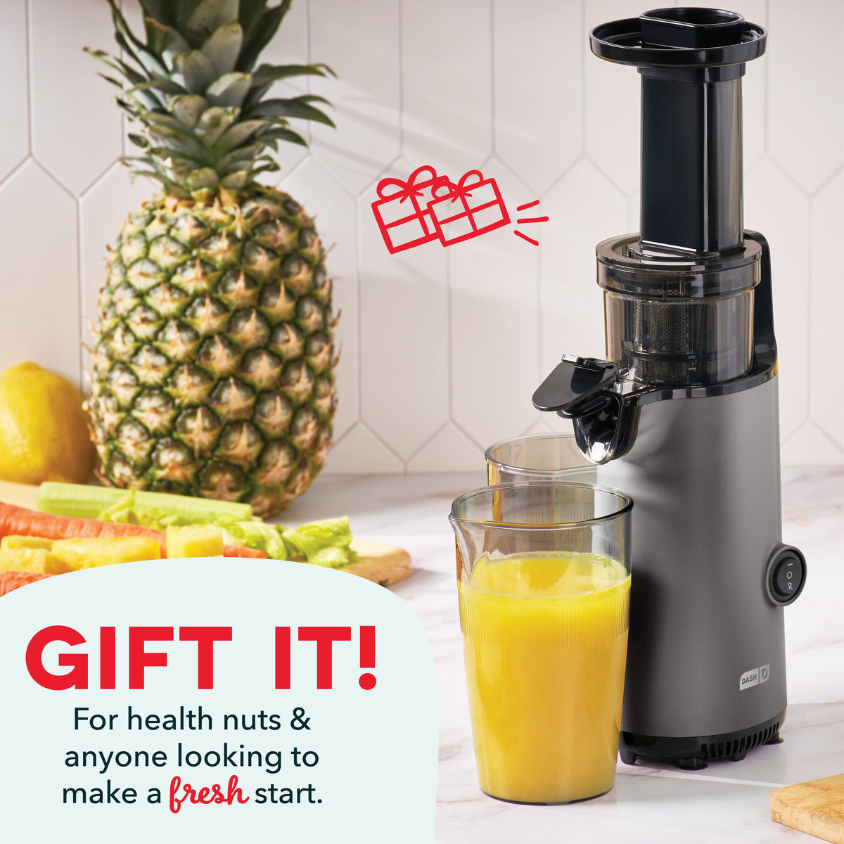 Black and gray vertical cold press juicer with juice collection glass, surrounded by pineapple, lemon, and vegetables.