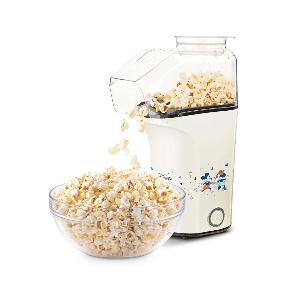 Cream-colored popcorn maker with Disney characters, dispensing popped popcorn into a clear bowl below.