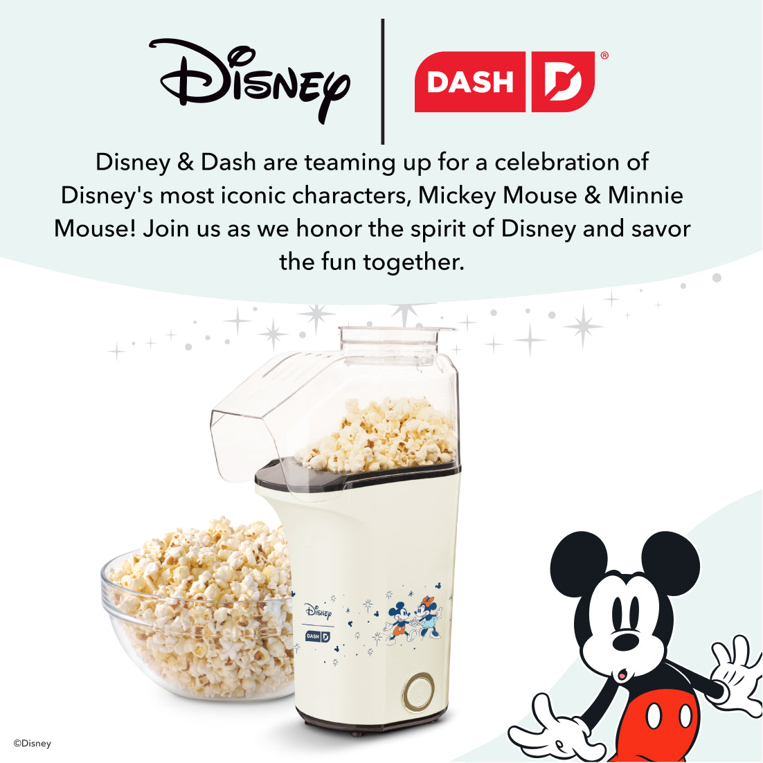 Cream-colored popcorn maker with Mickey Mouse design, popped popcorn in glass bowl and collection chute.