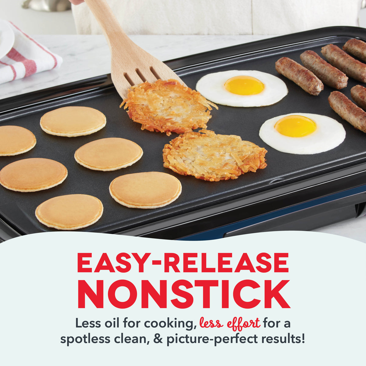 Black nonstick griddle cooking pancakes, hash browns, sausages, and fried eggs with wooden spatula.