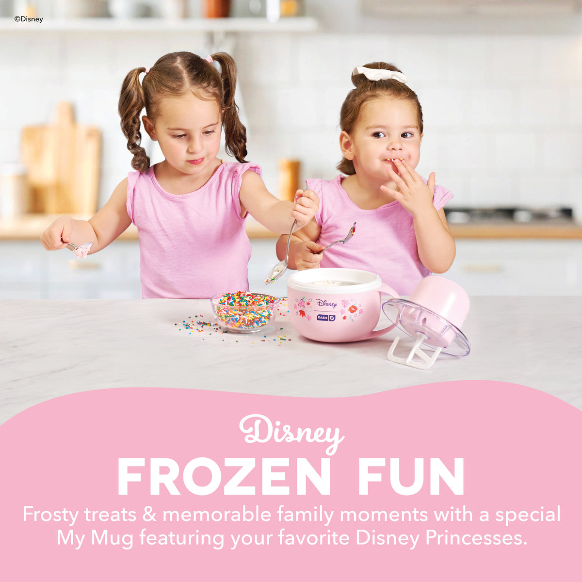 Two children using a pink mug-shaped ice cream maker with colorful sprinkles and clear paddle attachment on kitchen counter.
