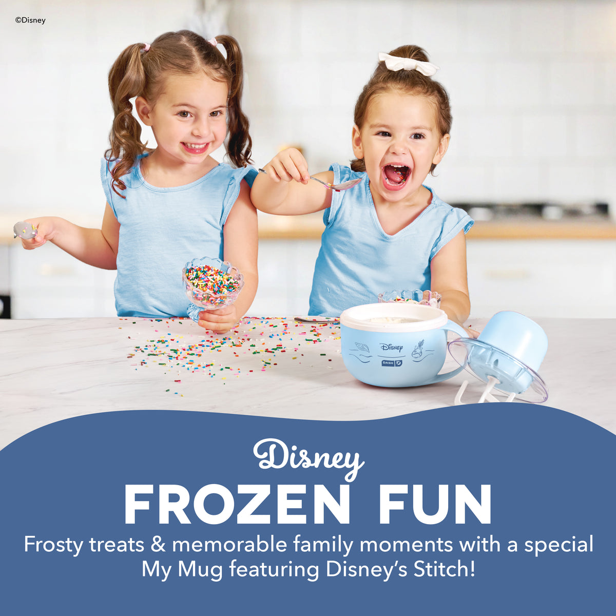 Two children in blue shirts using a light blue Disney ice cream maker with colorful sprinkles on a white table.