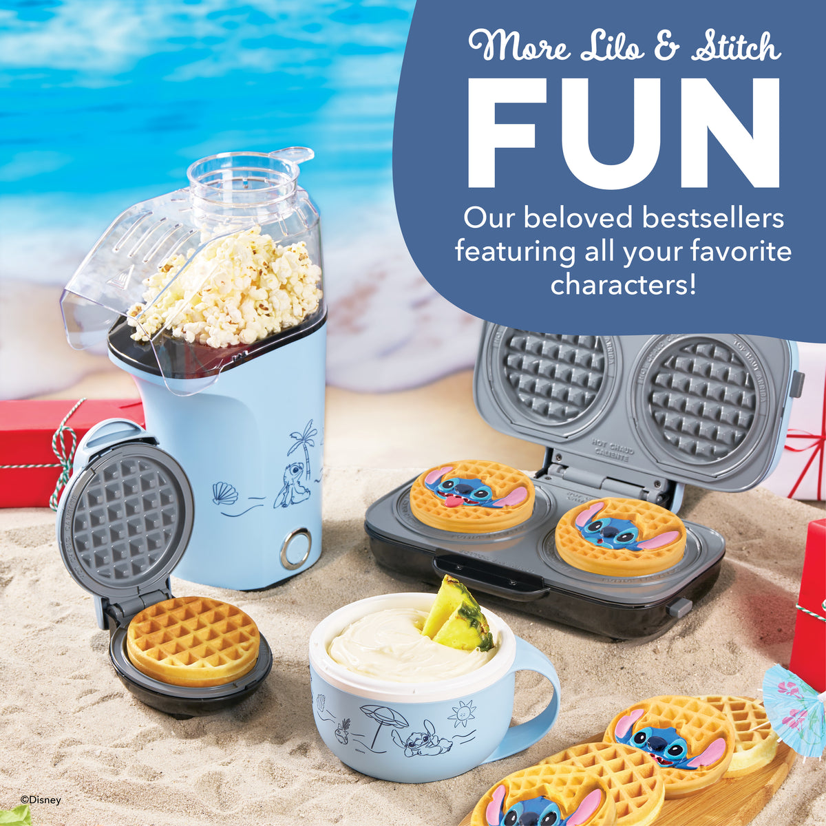 Blue mug-shaped ice cream maker with popcorn popper on top, displayed with waffle makers and character-themed waffles on beac