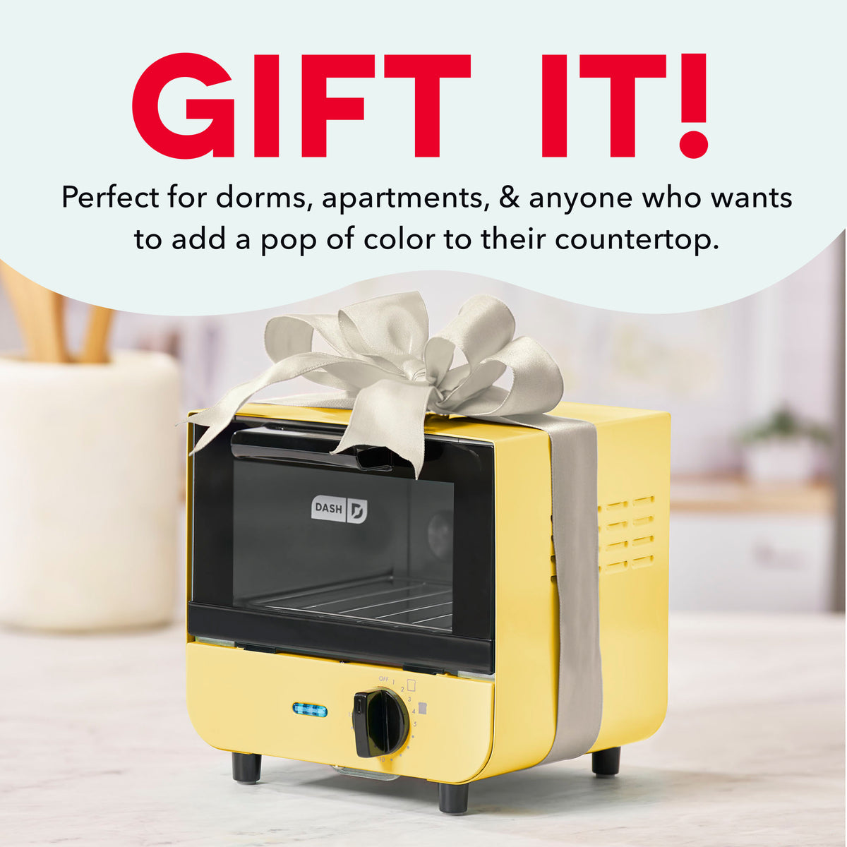 Yellow and black mini toaster oven with white bow on top, sitting on countertop.