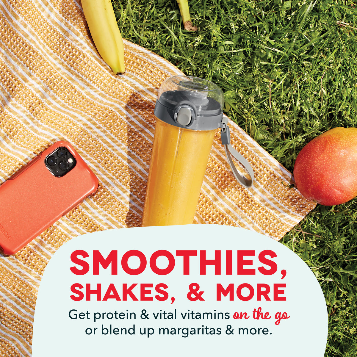 Yellow portable blender with black lid and carry strap on striped blanket, surrounded by banana, apple, and phone.