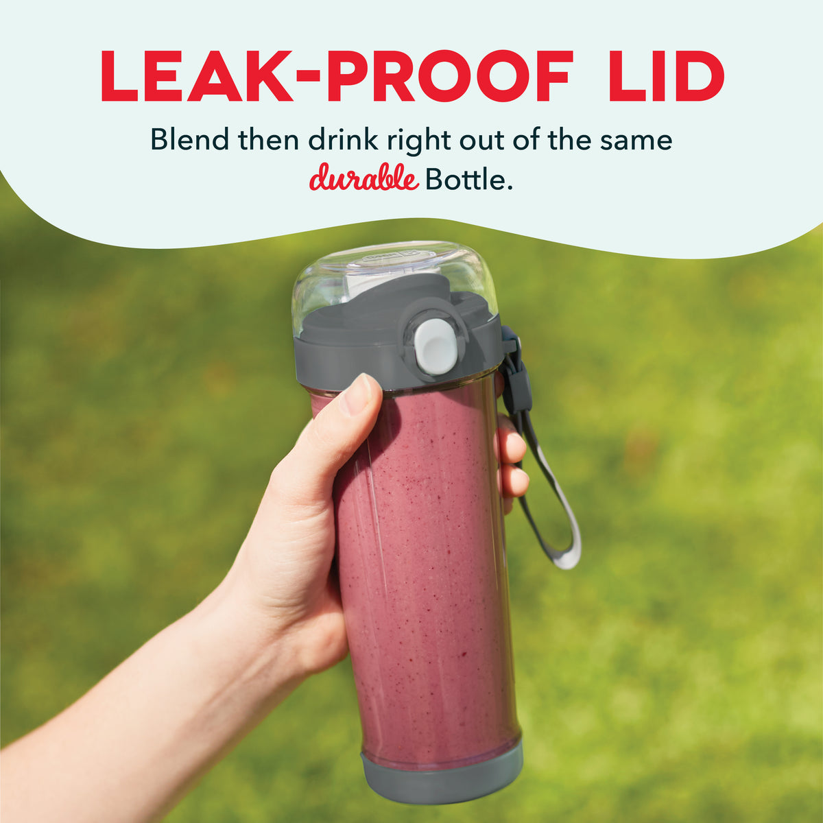 Person holding burgundy portable blender bottle with gray leak-proof lid and black carry strap outdoors.