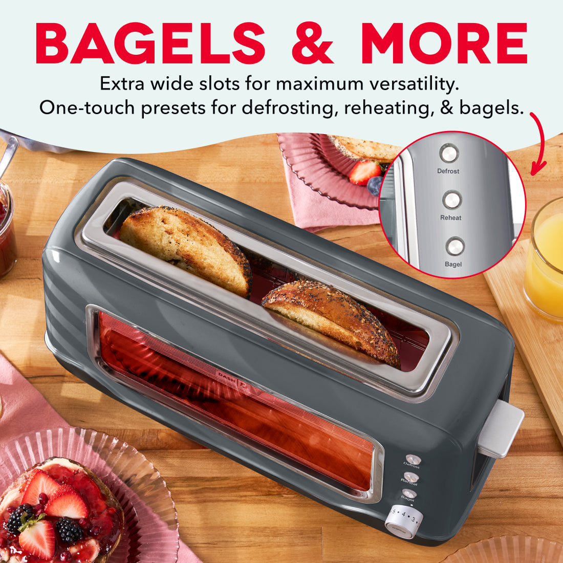 Gray toaster with wide slots and two toasted bagels inside, shown on wooden counter with fruit, juice, and control buttons vi