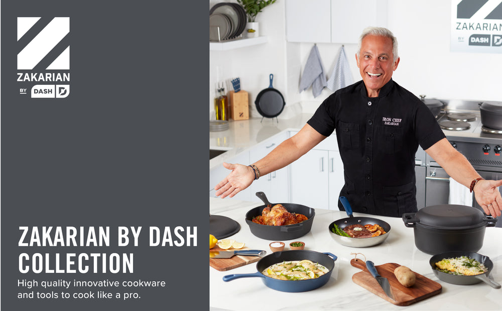 Geoffrey Zakarian in a kitchen wearing a black shirt gestures to the Zakarian by Dash collection displayed on a white countertop.  