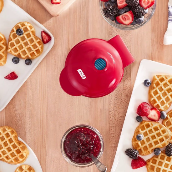 Waffle batter is added to the waffle maker and cooked to create a heart-shaped waffle.