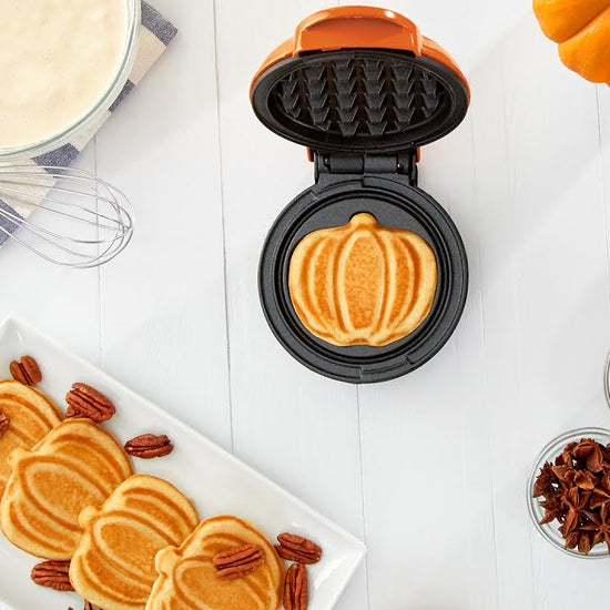 Waffle batter is added to the maker and cooked to make pumpkin-shaped mini waffles.